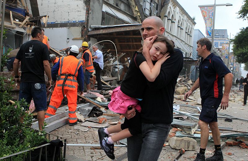 Uno hombre sostiene en brazos a una niña tras el terremoto