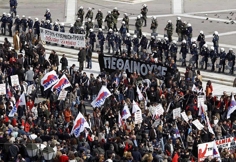 Los manifestantes marchan en frente del parlamento durante una huelga de 24 horas en Atenas este 23 de febrero de 2011. Las tiendas han cerrado sus escaparates y los servicios públicos estaban paralizados