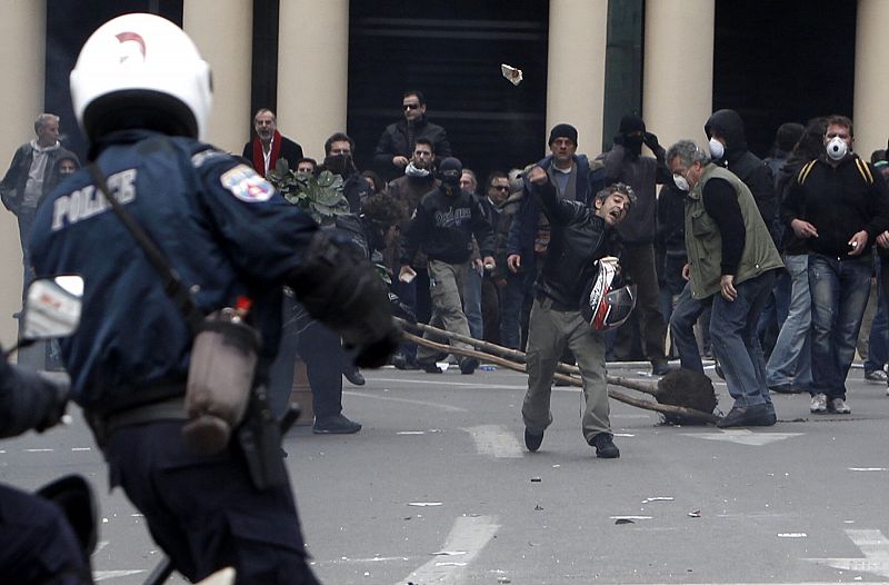 Los manifestantes arrojan piedras contra la policía, durante los enfrentamientos que se han producido frente al parlamento en Atenas