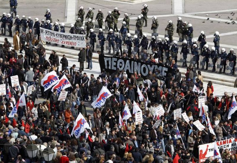 Los manifestantes marchan en frente del parlamento durante una huelga de 24 horas en Atenas este 23 de febrero de 2011. Las tiendas han cerrado sus escaparates y los servicios públicos estaban paralizados 