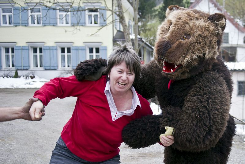 Un hombre disfrazado de oso asusta a una mujer durante la celebración del la costumbre carnavalesca "Bloch" en la región de Appenzell (Suiza).