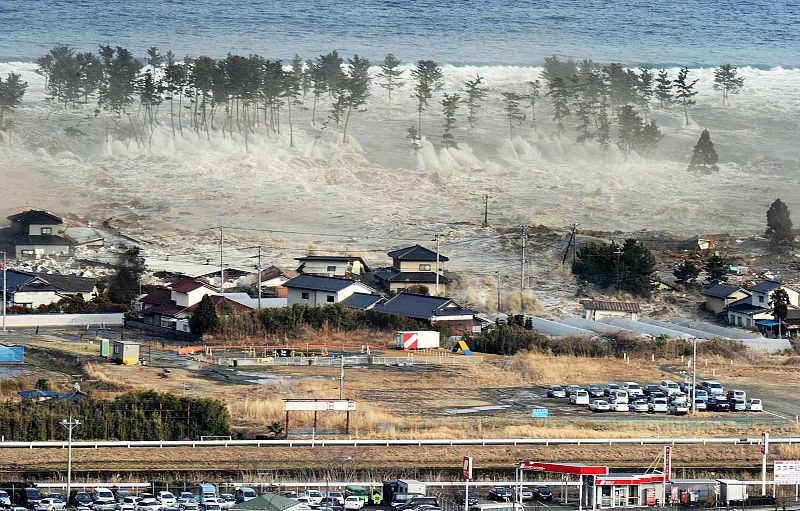 A massive tsunami sweeps in to engulf a residential area after a powerful earthquake in Natori