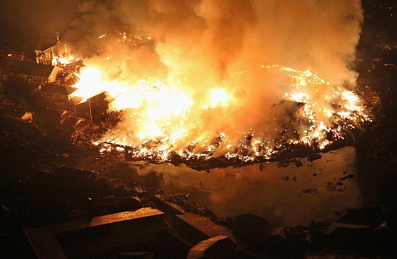 Houses burn at night following an earthquake in Natori City, Miyagi Prefecture, northeastern Japan