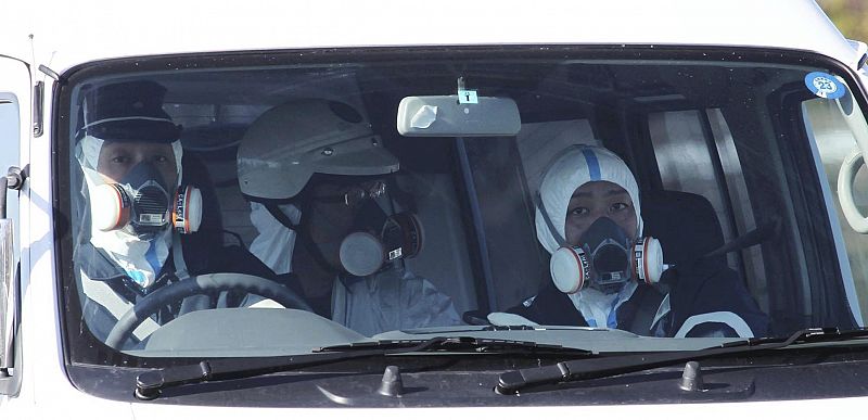 Police officers wearing respirators patrol around Fukushima Daiichi nuclear plant after an explosion in Fukushima Prefecture