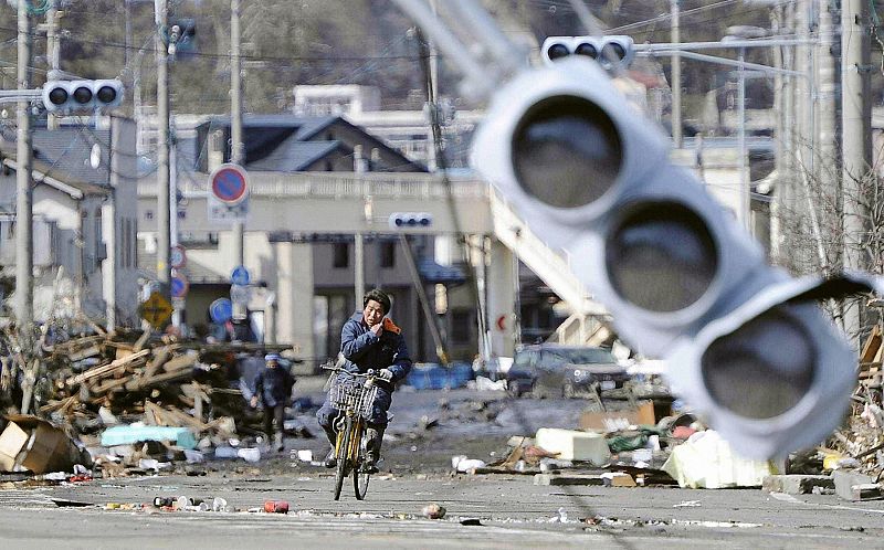 A man rides a bicycle through a debris-strewn street in Miyako, Iwate Prefecture in northeastern Japan