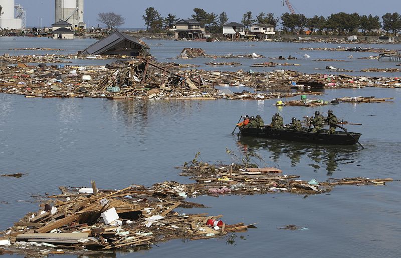 Self-Defense Force officers search for missing people by a boat after a tsunami and earthquake in Souma City