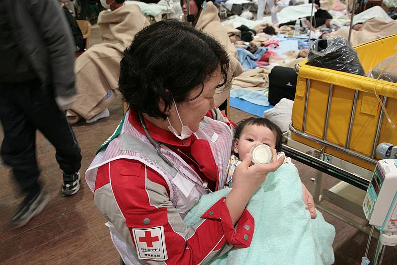 A member of the Japanese Red Cross feeds a baby, a survivor of an 8.9-magnitude earthquake and tsunami, at Ishinomaki Red Cross hospital in Miyagi prefecture