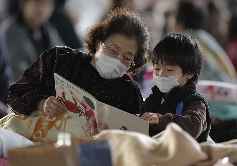 A boy reads a book with his grandmother at an evacuation centre set in a gymnasium in Yamagata, northern Japan