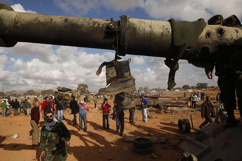 Boots of soldiers loyal to Libyan leader Muammar Gaddafi hang from a destroyed tank after an air strike by coalition forces, along a road between Benghazi and Ajdabiyah