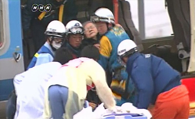 Emergency service workers transport a rescued woman to a hospital in Ishinomaki