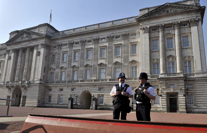 Un par de policías vigilan a las puertas del Palacio de Buckingham desde donde se prevé que el príncipe Guillermo y Kate Middleton saluden a la gente, y se besen, tras la boda