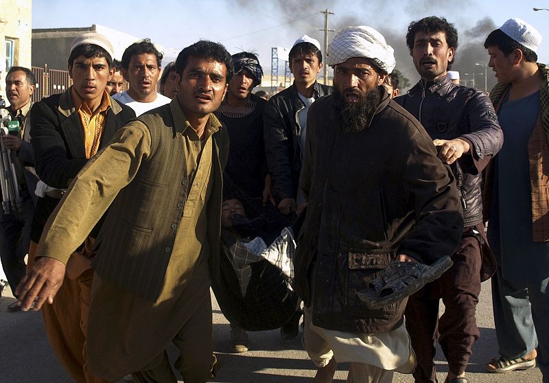 Afghans carry a man who was wounded following an attack on an United Nations compound, during a demonstration to condemn the burning of a copy of the Muslim holy book by a U.S. pastor, in Mazar-i- Sharif