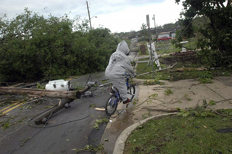 Una persona trata de pasar con su bicicleta por entre los escombros de casas y negocios destrozados por fuertes tormentas y tornados en Pratt City