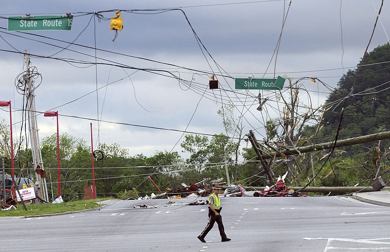 Un agente de policía atraviesa una calle en la que el tendido eléctrico y telefónico fue arrasado por el tornado