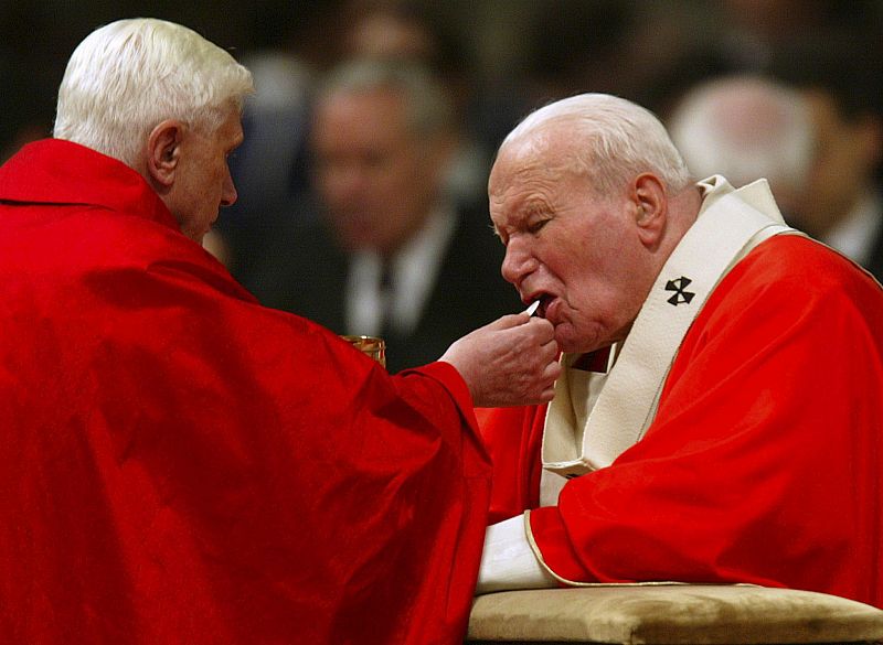 Imagen de archivo tomada el 09 de abril de 2004 que muestra al cardenal Joseph Ratzinger dando la comunión al papa Juan Pablo II un año antes de su muerte