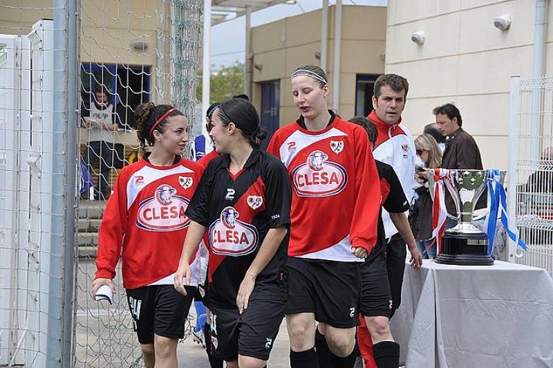 Las jugadoras del Rayo pasan junto a la copa de la Superliga antes del partido frente al Espanyol donde se proclamarían campeonas. Al fondo, el técnico rayista, Joserra Hernández.