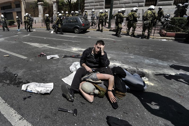 Manifestantes sentados en el pavimento después de los enfrentamientos con la policía en Atenas