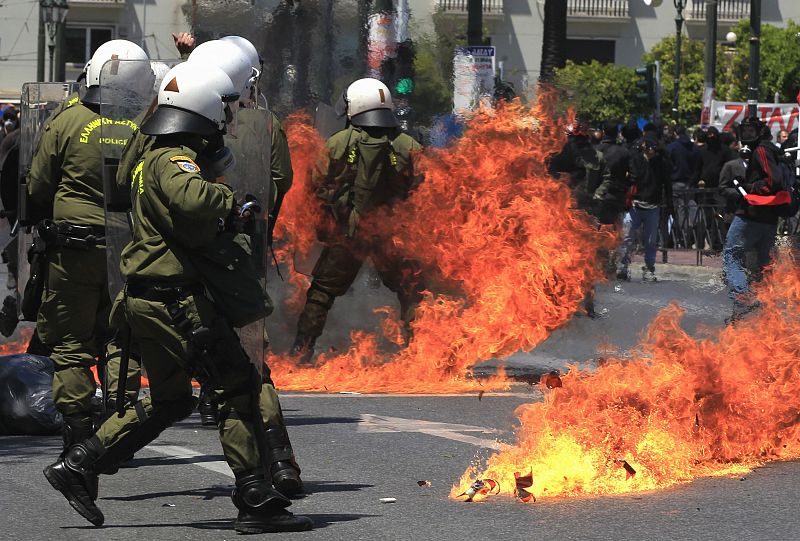 Un agente de policía corre para protegerse del lanzamiento de un cóctel molotov por los manifestantes