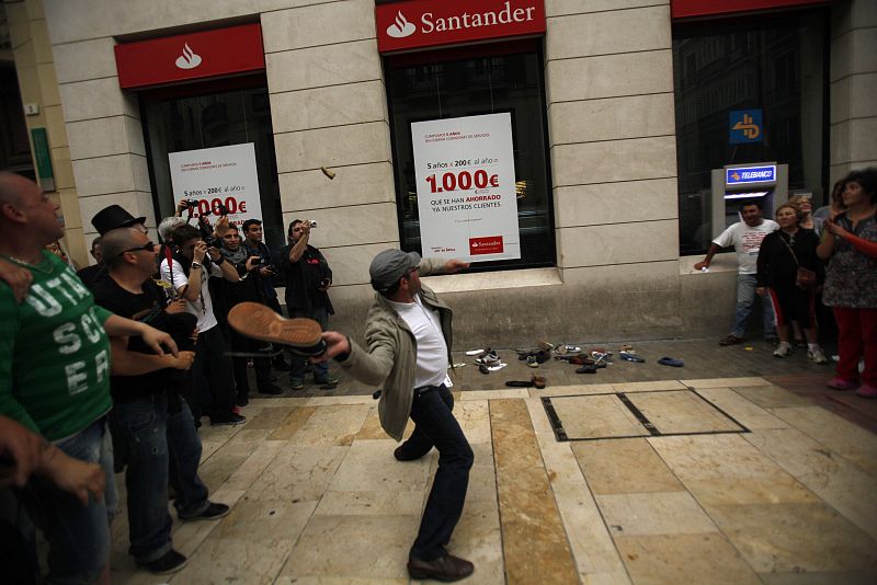 A demonstrator throws a shoe at Santander bank during a demonstration in Malaga