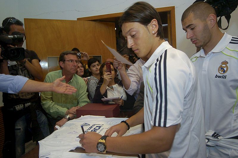 El centrocampista alemán del Real Madrid Mesut Ozil, acompañado de su compañero el delantero francés Karim Benzema, firma una camiseta en el Ayuntamiento de Lorca.