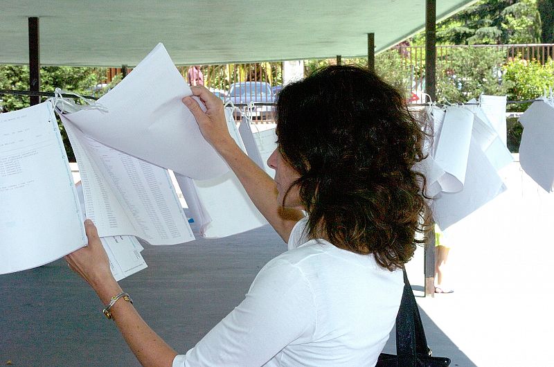 Una joven busca su mesa electoral en el censo colgado a la entrada de un colegio electoral en Madrid.