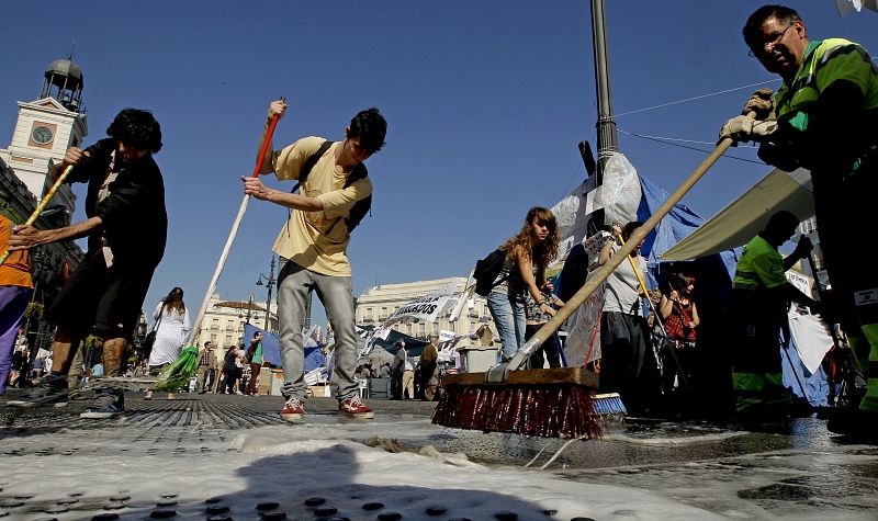 Varias personas limpian el suelo en la Puerta del Sol de Madrid.