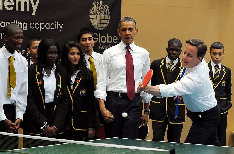 Obama observa a su compañero de juego, Cameron, durante la partida de pin-pon