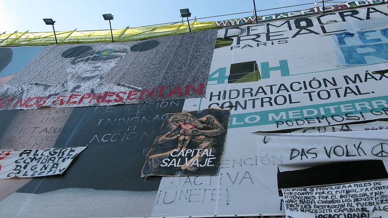 Este muestrario de carteles que hay en este edificio, entre las calle del Carmen y Preciados, se ha quedado como "un símbolo", explica Pedro, uno de los 'indignados'.