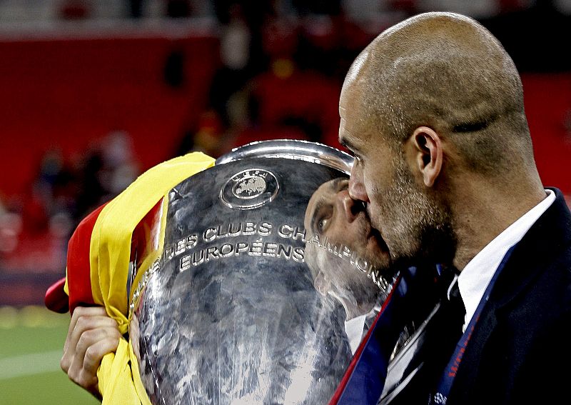 El entrenador del FC Barcelona, Pep Guardiola, besa el trofeo de campeón de la Liga de Campeones tras vencer el conjunto azulgrana.
