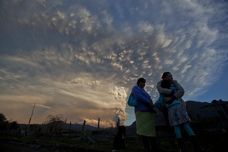 Mujeres conversan frente a la erupción del complejo volcánico.