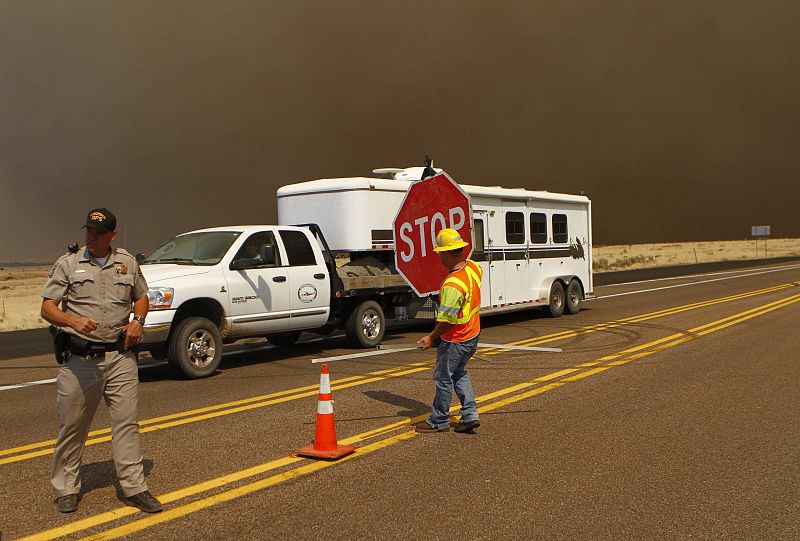 Un policía dirige el tráfico y se dispone a cerrar un tramo de la autopista número 60 debido al incendio