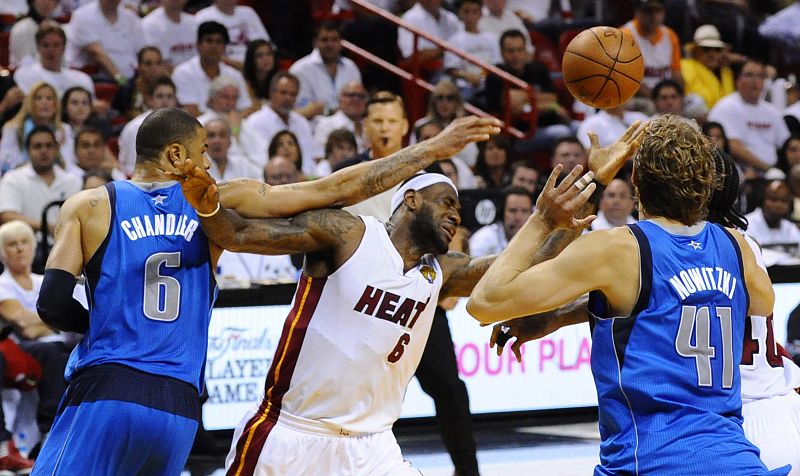 El jugador Tyson Chandler (c) de los Mavericks de Dallas en acción ante la defensa de Mike Miller (i) y Eddie House (d) de los Heat de Miami durante el sexto juego de la NBA.