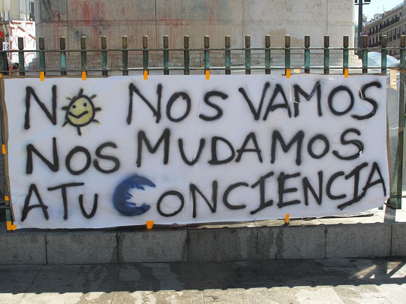 Pancarta colocada en la estatua de Carlos III, ubicada en el centro de la Puerta del Sol de Madrid: "No nos vamos, nos mudamos a tu conciencia".