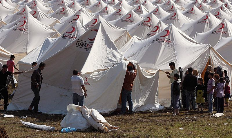 Personal de la Cruz Roja prepara una tienda de campaña en un campo de refugiados.