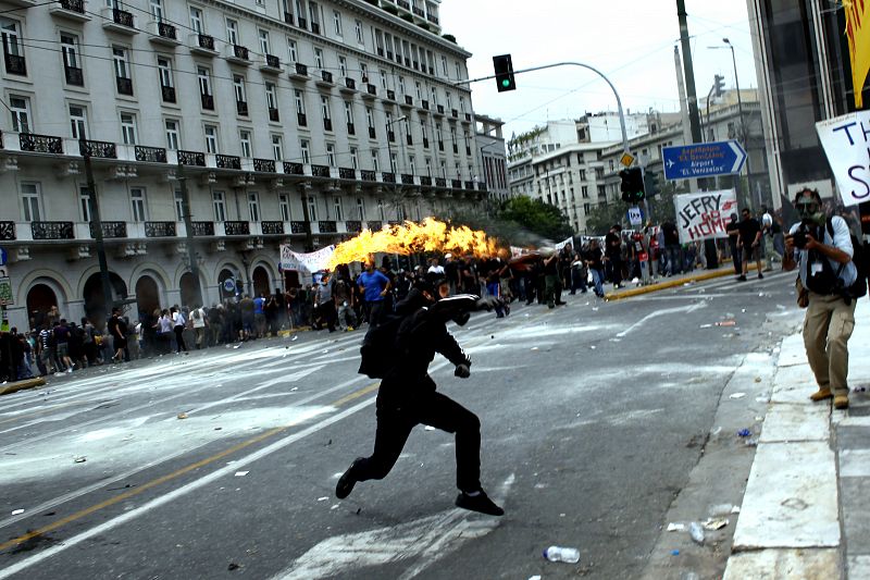 Un manifestante lanza un cóctel molotov en una de las calles adyacentes a la plaza Sintagma