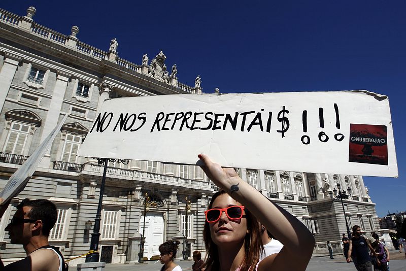 Demonstrators holding banners walks past the Royal palace as they march towards Spanish parliament in Madrid