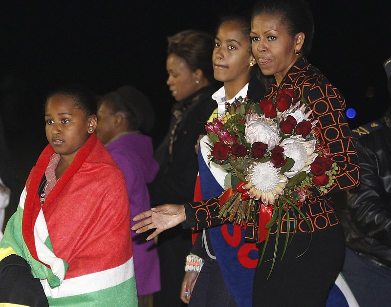 Michelle Obama y sus hijas Malia y Sasha envueltas en la bandera sudafricana llegan a la base aérea Waterkloof.