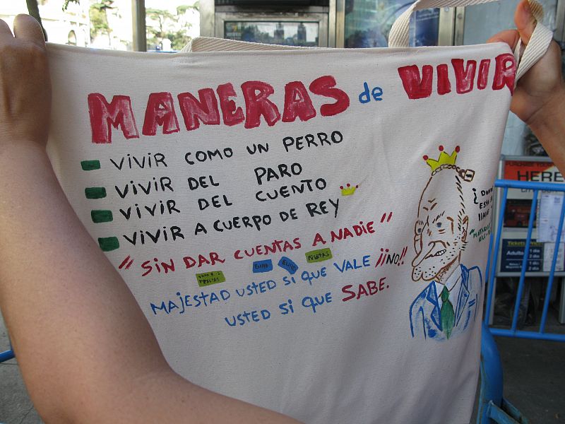 Una de las concentradas muestra un cartel con críticas a la Corona