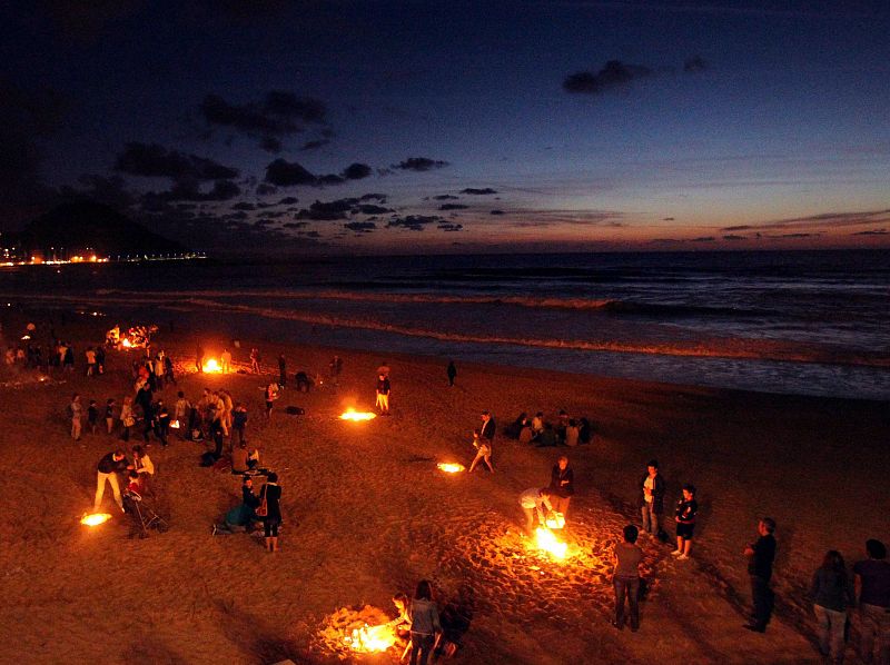 Asistentes a la tradicional noche de San Juan celebran la llegada del verano en la playa de La Zurriola de San Sebastián.