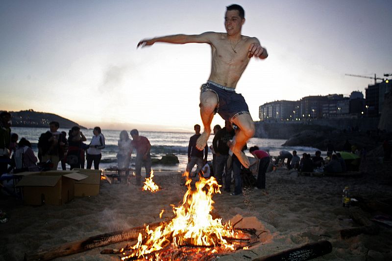 Un joven salta una hoguera en la coruñesa playa del Orzán.