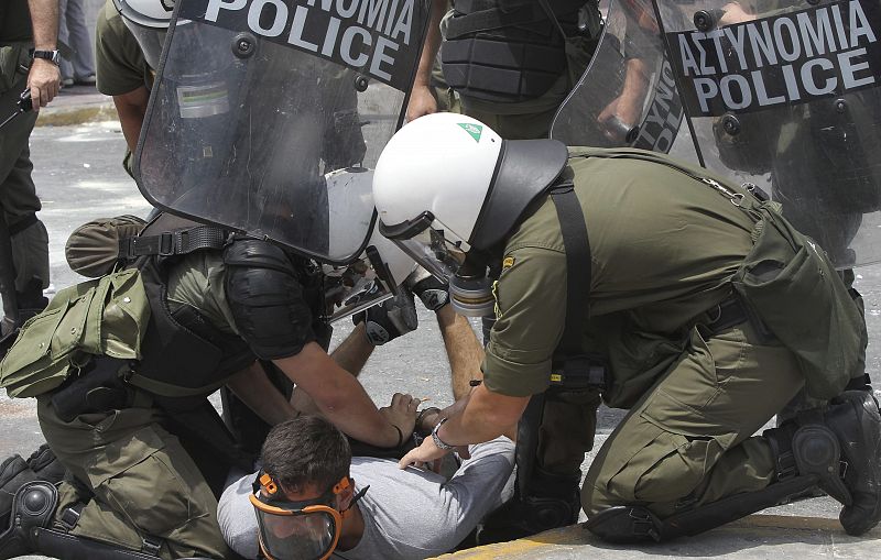 Un manifestante con máscara antigás siendo detenido por policías antidisturbios en la plaza Syntagma