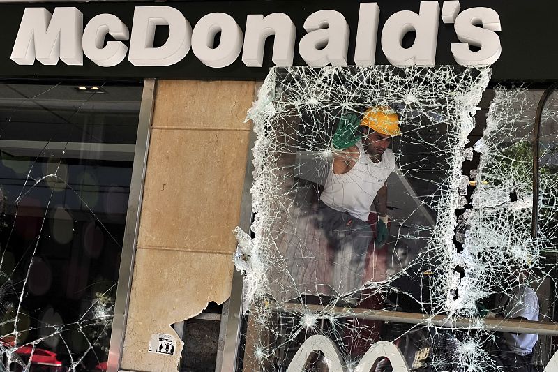 Un hombre retira una ventana rota de Mcdonald's, un establecimiento de comida rápida ubicado en la plaza Syntagma en el centro de Atenas.