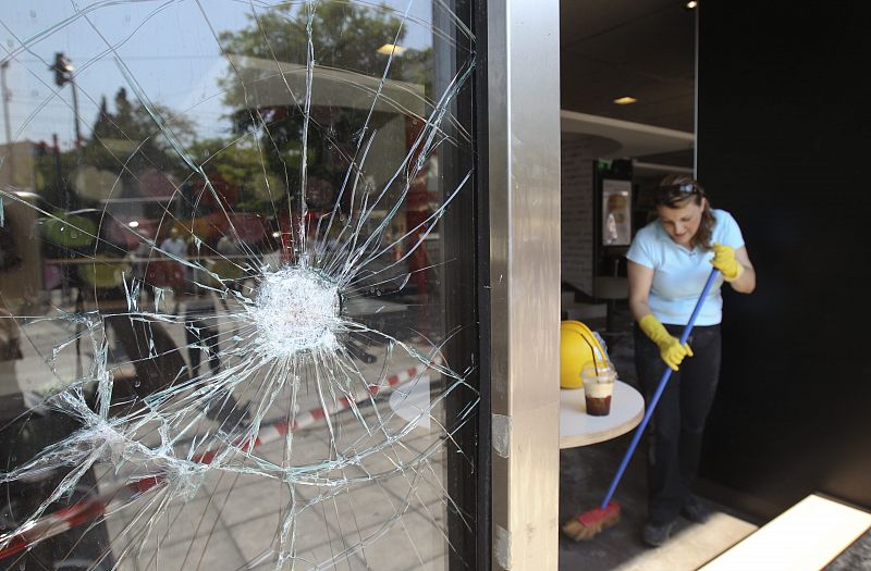 Una mujer barre los vidrios rotos del piso de un restaurante de comida rápida. Las calles de la capital griega estaba en calma el jueves antes de la votación prevista para la aprobación del proyecto de austeridad.