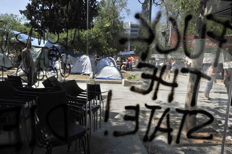 Las manifestaciones de los 'indignados' se reflejan en lemas esritos en los escaparates de establecimientos como este, en una cafetería, en Atenas.