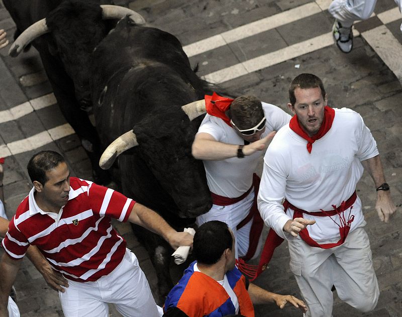 Uno de los toros mete el cuerno por debajo del pañuelo de uno de los participantes