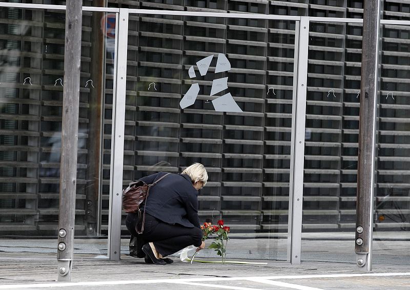 A woman lays down flowers next to the entrance of the Nordic embassies to Germany in Berlin
