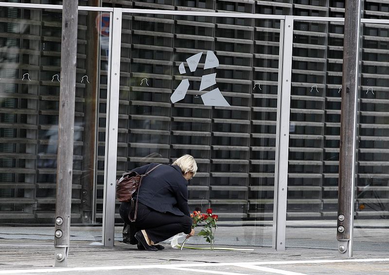 A woman lays down flowers next to the entrance of the Nordic embassies to Germany in Berlin