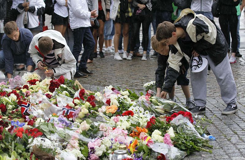 Norwegian boys place flowers on the cobble stones of the market square outside the Oslo cathedral to mourn the victims of a bomb blast and a rampage