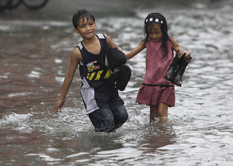 Dos niños caminan por las calles inundadas de malobón, al norte de Manila