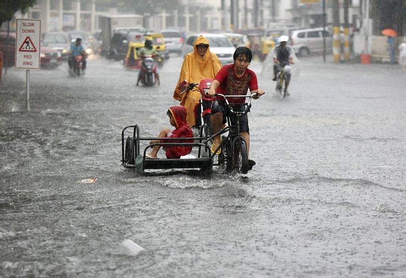 Un pequeño cruza la calle inundada en la Ciudad de las Las Pinas